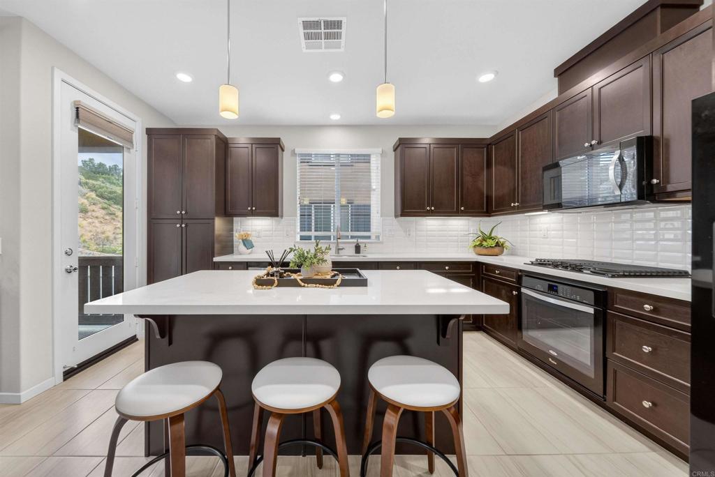387 Mission Villas Road San Marcos, CA 92069 - Photo 7 of 45 a kitchen with stainless steel appliances kitchen island granite countertop a sink and chairs
