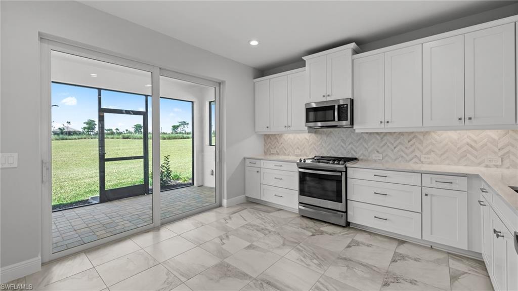 4641 Centaurus Circle Naples, FL 34120 - Photo 19 of 31 a kitchen with stainless steel appliances granite countertop a stove a sink and a white cabinets