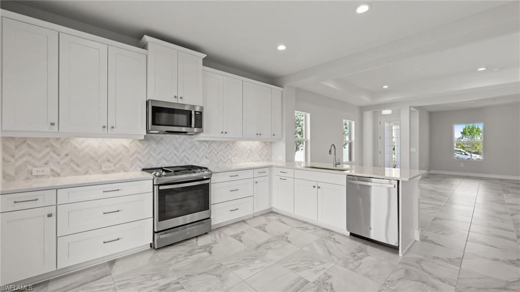 4641 Centaurus Circle Naples, FL 34120 - Photo 21 of 31 a kitchen with granite countertop white cabinets white stainless steel appliances and sink