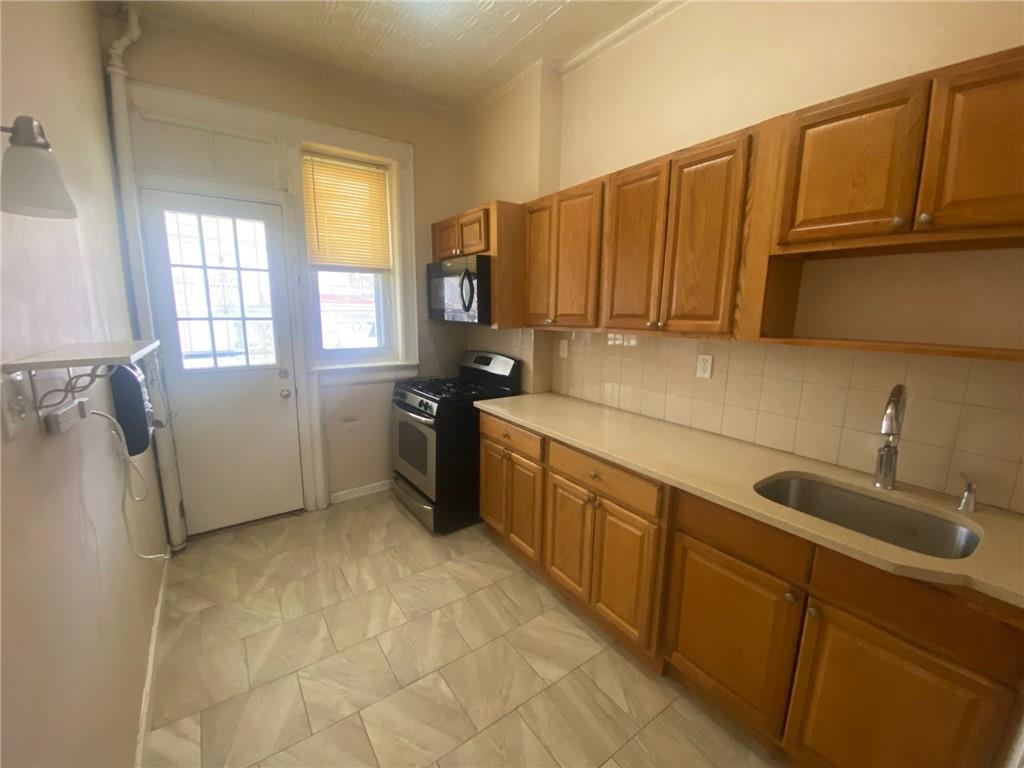 630 53rd Street Brooklyn, NY 11220 - Photo 4 of 14 a kitchen with stainless steel appliances granite countertop a sink a stove and a refrigerator