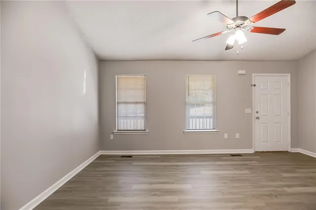 a view of an empty room with window and wooden floor