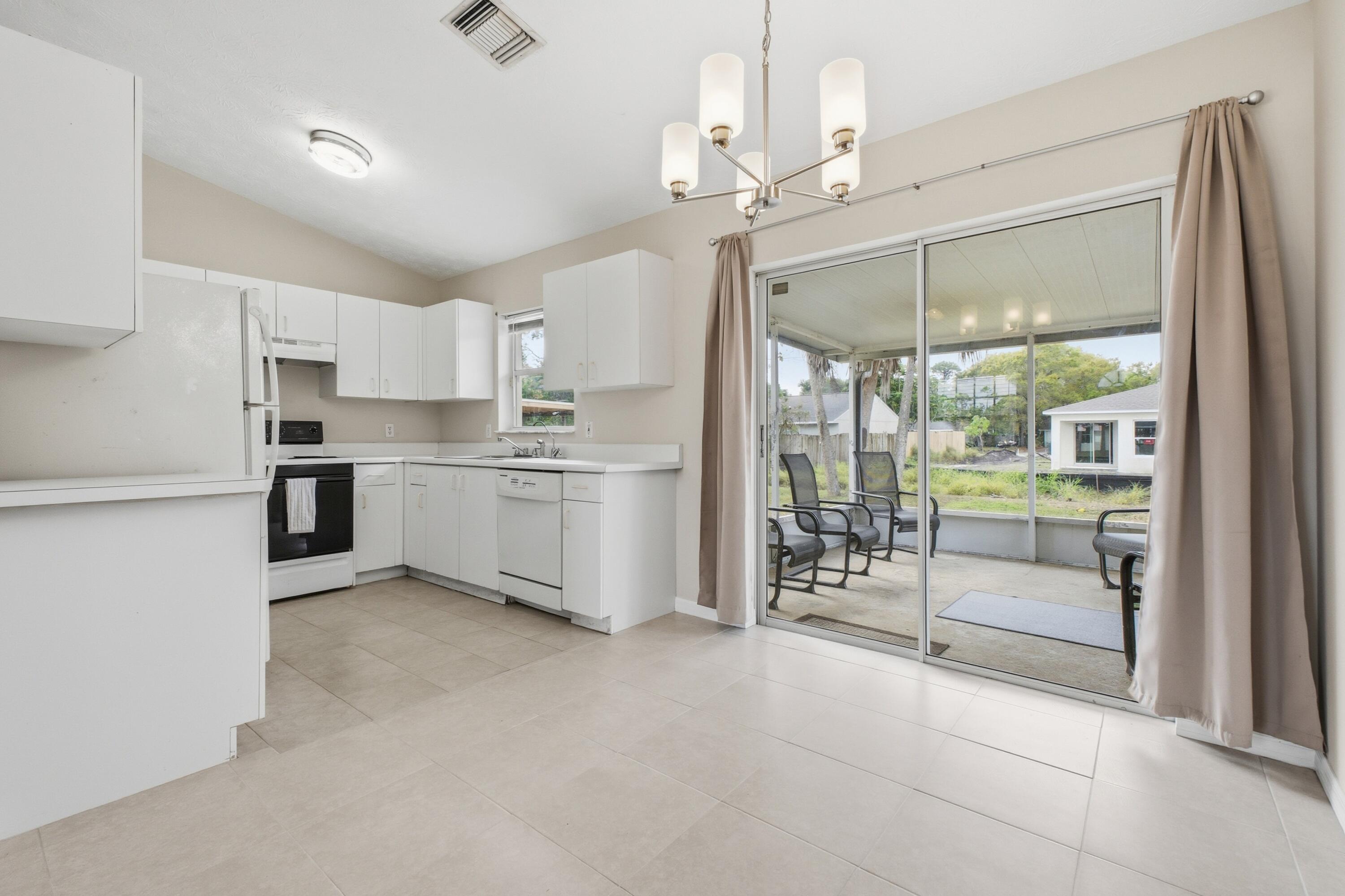 5809 Killarney Avenue Fort Pierce, FL 34951 - Photo 6 of 29 a open kitchen with a refrigerator a stove top oven a sink and a large window