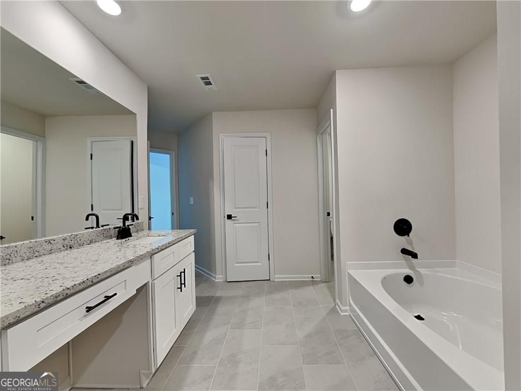 3323 Arabian Farm Lane Dacula, GA 30019 - Photo 13 of 24 a bathroom with a granite countertop tub a double vanity sink and mirror