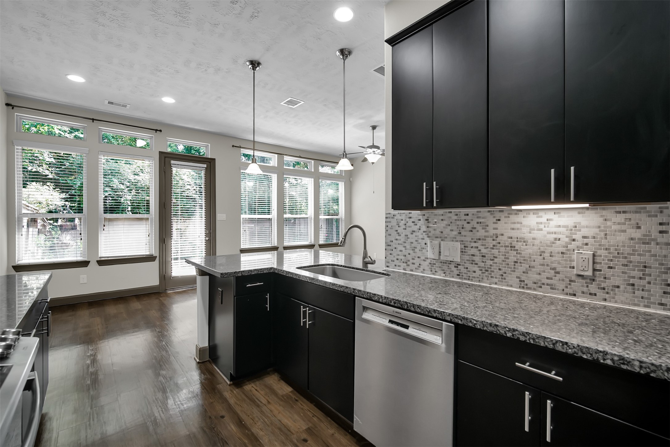 111 Aventura Place Spring, TX 77389 - Photo 18 of 42 a kitchen with stainless steel appliances granite countertop sink stove and wooden floor