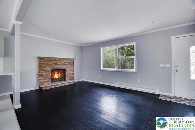 an empty room with wooden floor a fireplace and windows