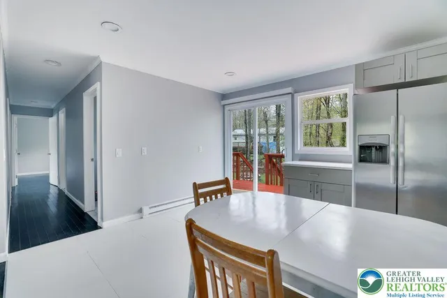 a living room with stainless steel appliances furniture a large window and a kitchen view