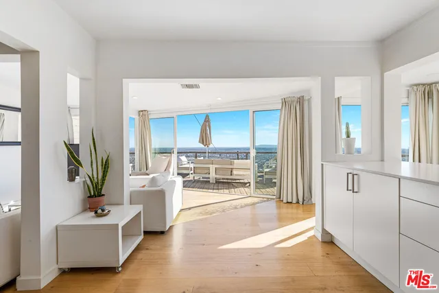 a living room with furniture a large window with kitchen view