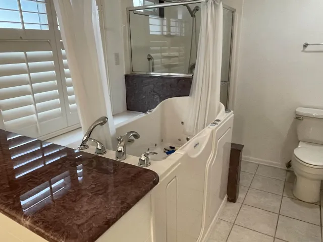 a bathroom with a granite countertop sink a toilet and shower