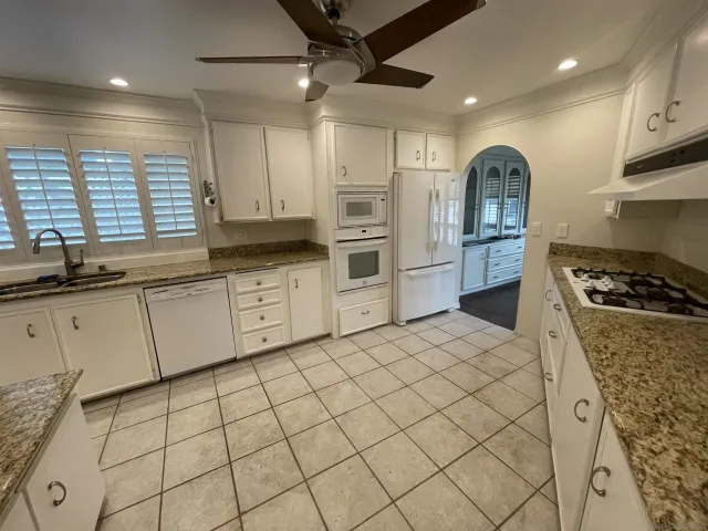 a kitchen with white cabinets a sink a stove and a refrigerator