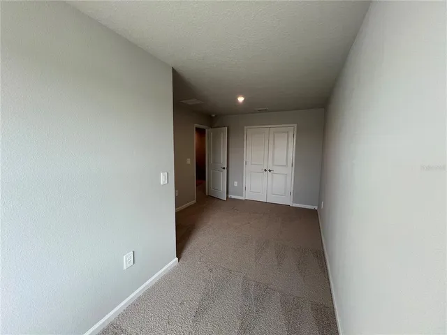 an empty room with closet and windows