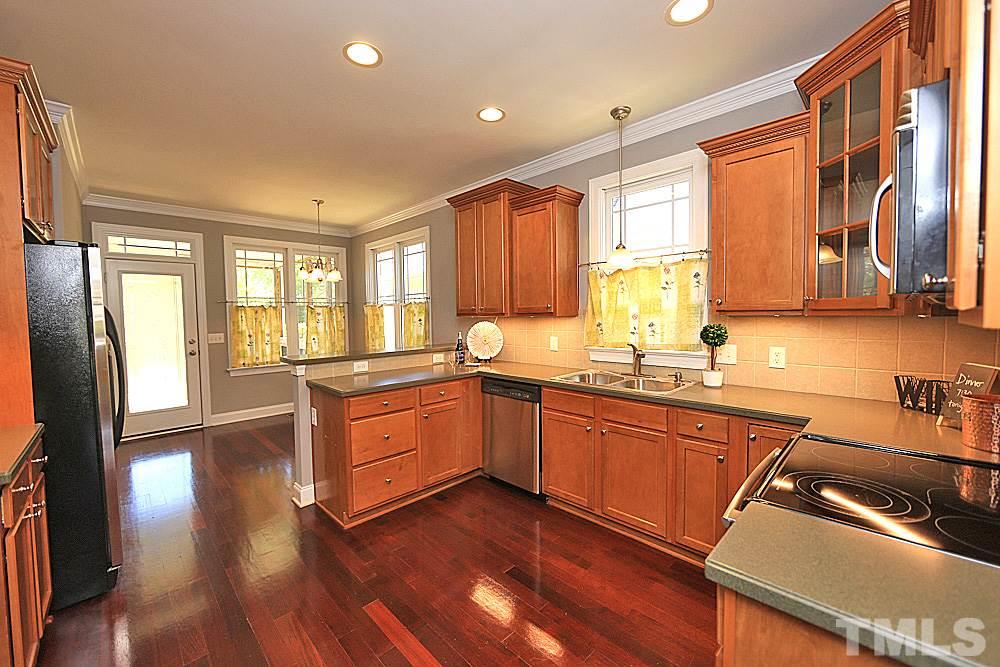2108 Karns Place Raleigh, NC 27614 - Photo 8 of 26 a kitchen with granite countertop wooden floors wooden cabinets and stainless steel appliances