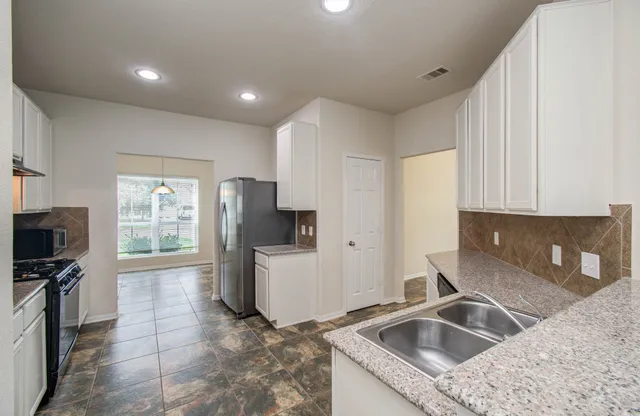 a kitchen that has a sink cabinets counter space and appliances