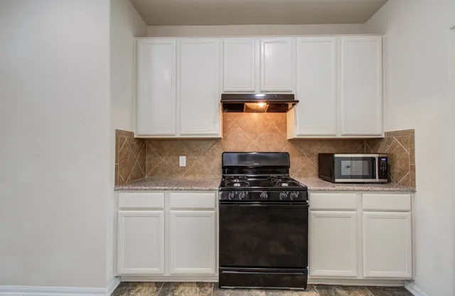 a kitchen with white cabinets and black appliances