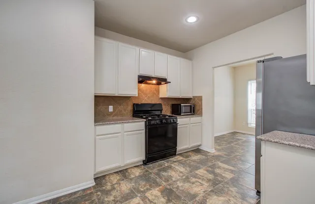 a kitchen with a stove top oven and cabinets