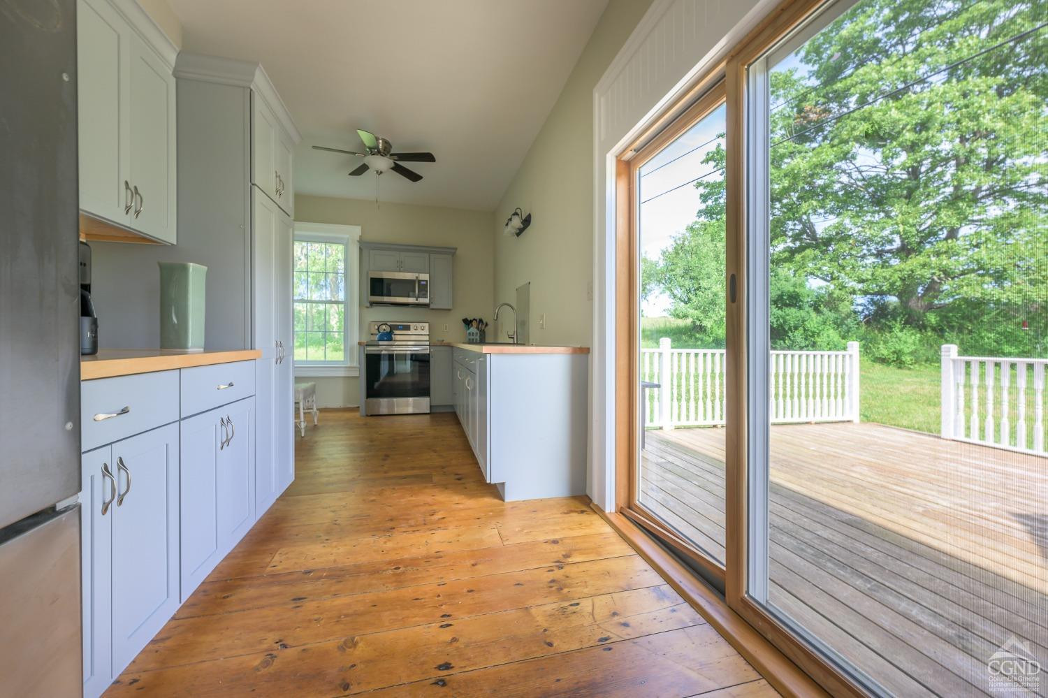 235 Slate Hill Road Ghent, NY 12037 - Photo 16 of 38 a large kitchen with kitchen island wooden floors a large window and stainless steel appliances