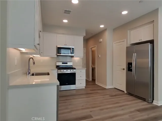 a large kitchen with stainless steel appliances granite countertop a refrigerator a sink a stove a microwave and a refrigerator