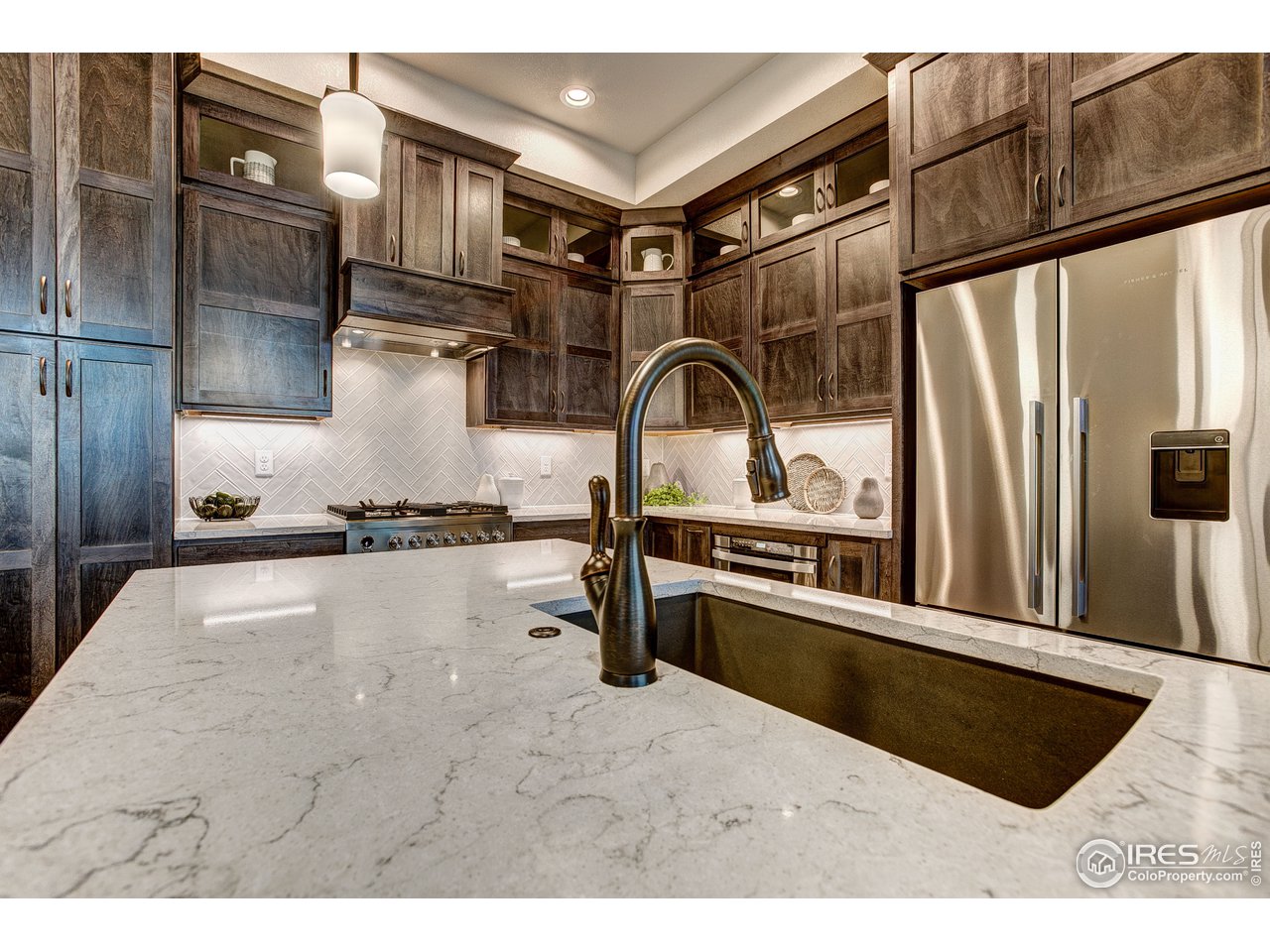 1547 Stoneseed Street Berthoud, CO 80513 - Photo 18 of 39 a kitchen with stainless steel appliances granite countertop a refrigerator a stove and a sink with wooden cabinets