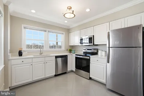 a kitchen with granite countertop white cabinets and refrigerator