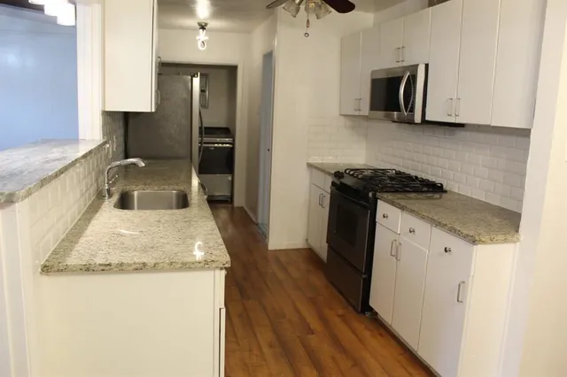 a kitchen with granite countertop a sink and a stove top oven