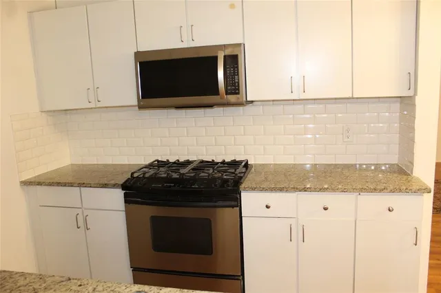 a kitchen with stainless steel appliances granite countertop white cabinets and a stove