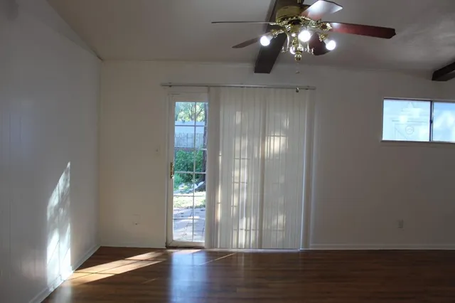 a view of empty room with wooden floor and fan
