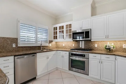 a kitchen with granite countertop white cabinets sink and stainless steel appliances