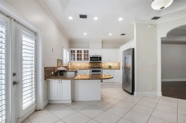 a kitchen with stainless steel appliances kitchen island granite countertop a refrigerator and a sink