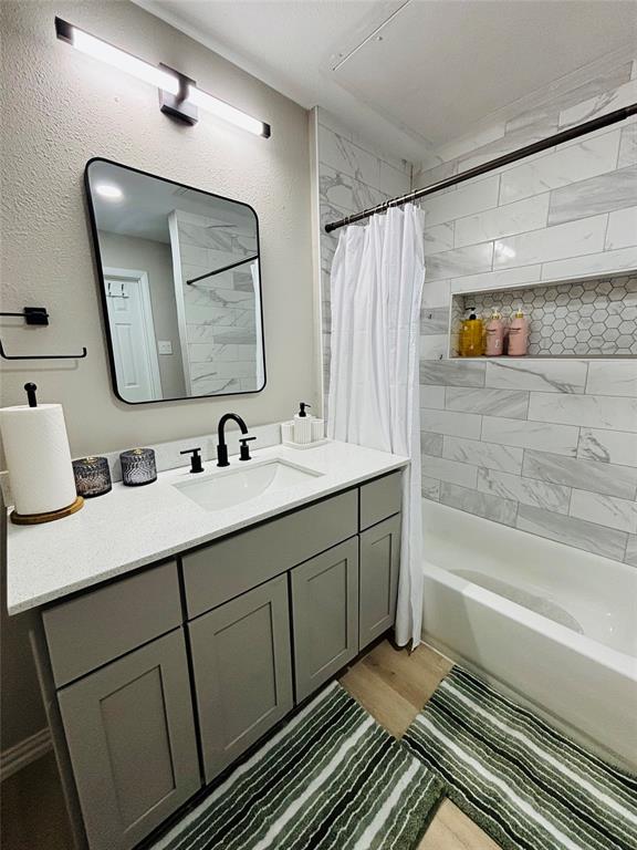 14277 Preston Road, Unit 416 Dallas, TX 75254 - Photo 24 of 40 Bathroom with a single vanity featuring a white countertop and gray cabinetry, black fixtures, and wood-finish flooring