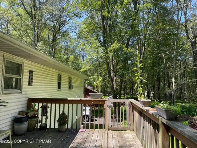 a view of a wooden deck and a yard with large tree