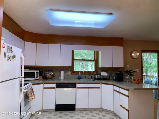 a kitchen with granite countertop a refrigerator a sink a stove a microwave and cabinets