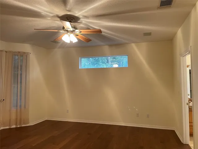 an empty room with wooden floor fan and window