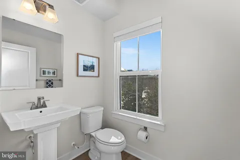 a bathroom with a toilet a sink a mirror and a window