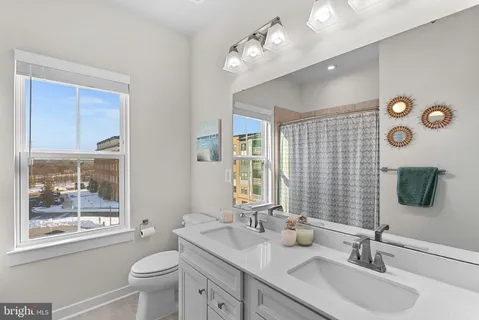 a bathroom with a granite countertop sink mirror vanity and next to a window