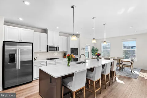 a kitchen with stainless steel appliances kitchen island granite countertop a dining table chairs and white cabinets