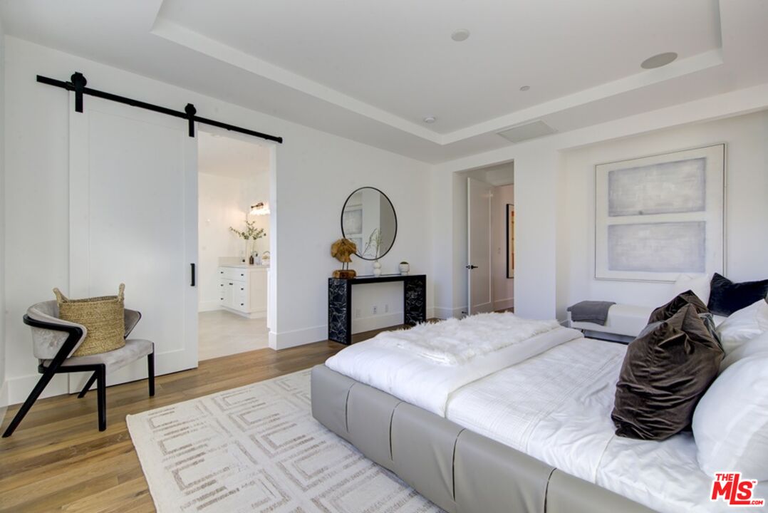 10810 Valley Spring Lane Studio City, CA 91602 - Photo 29 of 36 a bedroom with a bed and a chair with the wooden floor