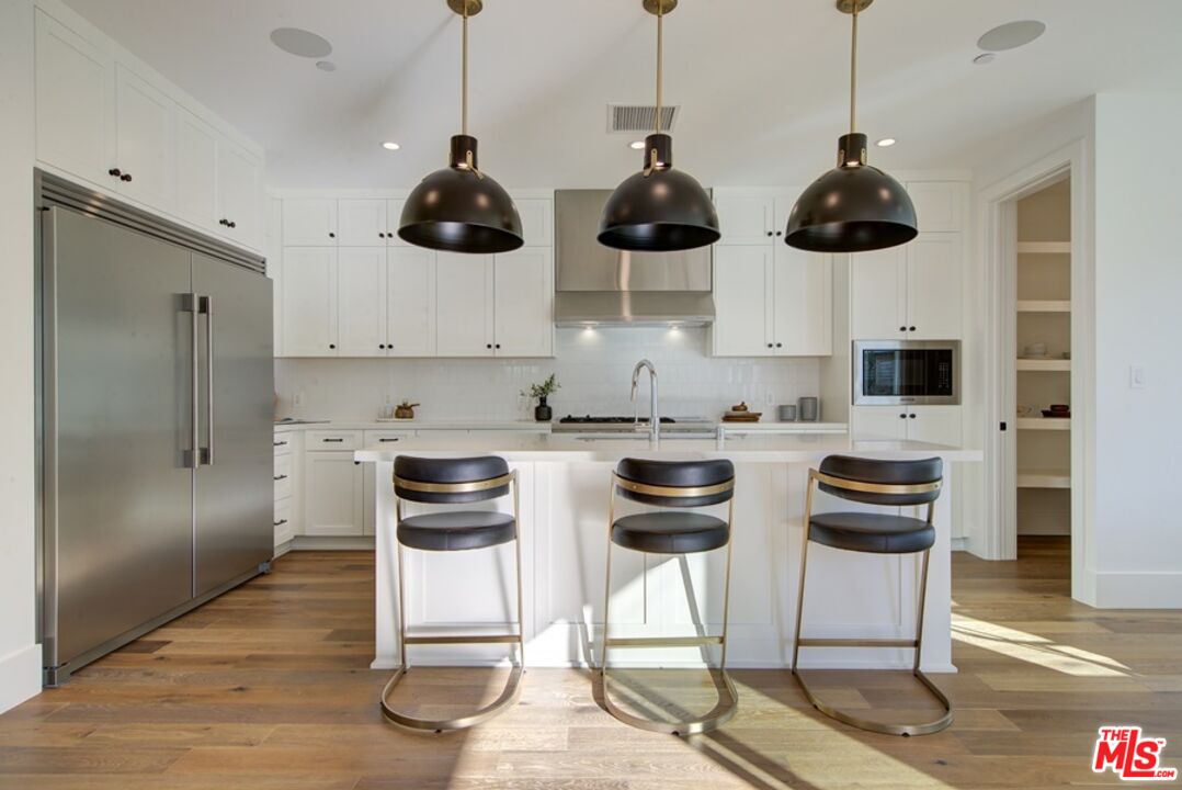 10810 Valley Spring Lane Studio City, CA 91602 - Photo 5 of 36 a kitchen with stainless steel appliances kitchen island granite countertop a table and chairs in it