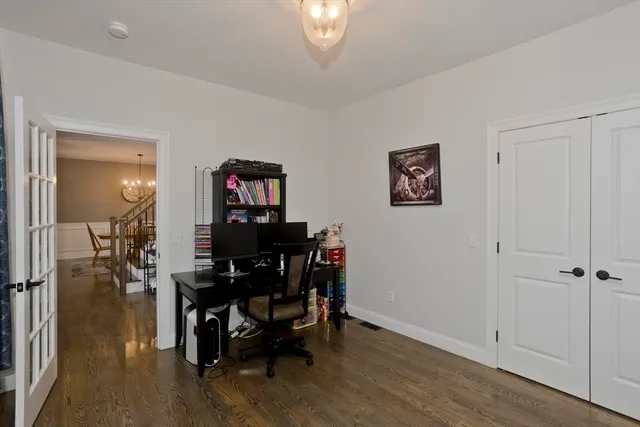 a view of a workspace room with wooden floor windows a chandelier and windows