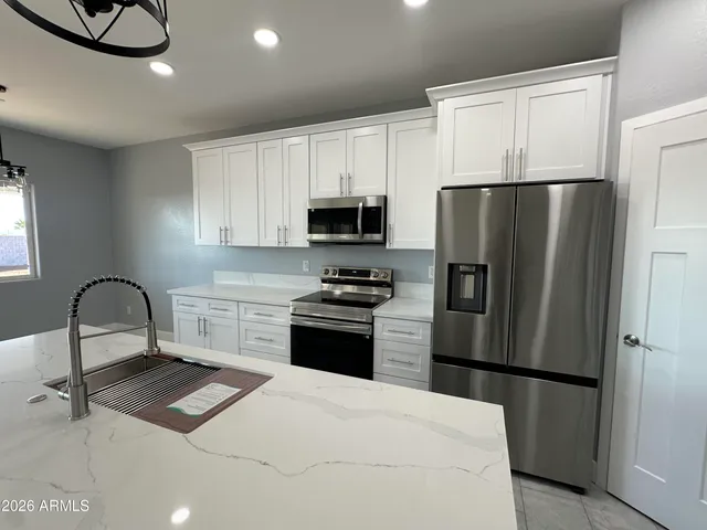 a kitchen with stainless steel appliances granite countertop a refrigerator a stove a microwave oven a sink and dishwasher