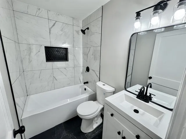 a bathroom with a sink a toilet a mirror and shower