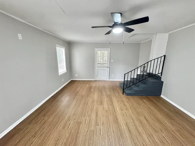 a view of an empty room with wooden floor and a window