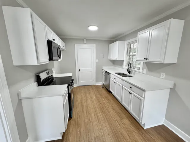 a kitchen with stainless steel appliances a sink a stove a refrigerator cabinets and a window