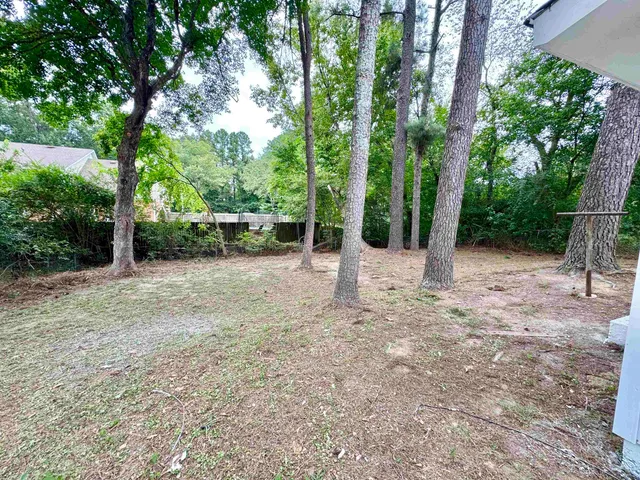 a view of a house with a backyard and trees