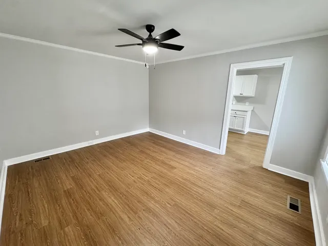 an empty room with wooden floor and windows