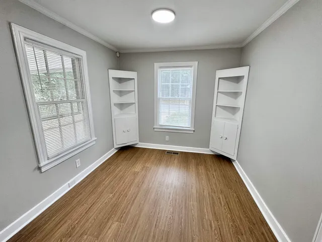 an empty room with wooden floor and windows