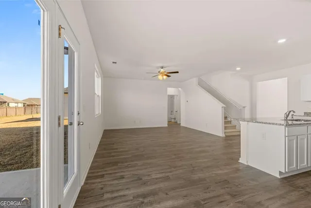 an empty room with wooden floor ceiling fan and windows
