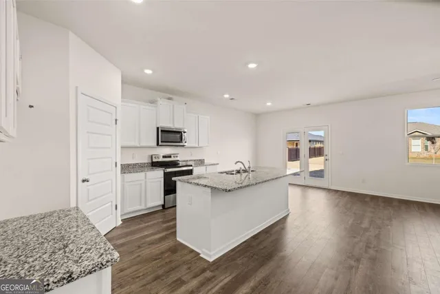 a kitchen with stainless steel appliances granite countertop a sink dishwasher stove and microwave with wooden floor