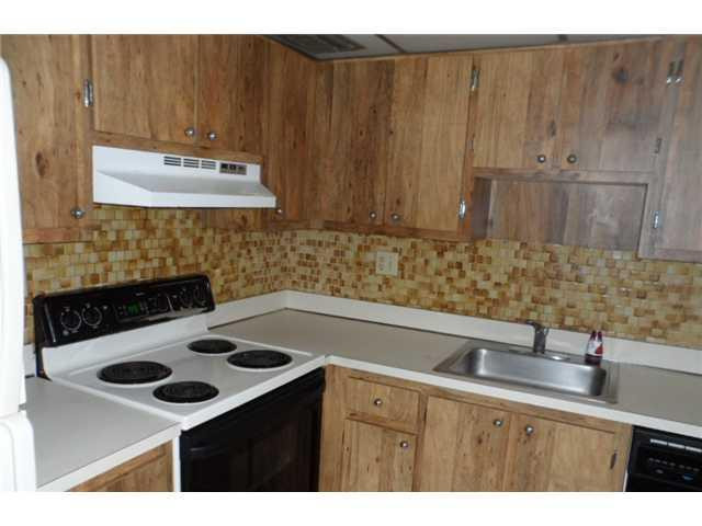9920 Northwest 68th Place, Unit 210 Tamarac, FL 33321 - Photo 6 of 12 a kitchen with a sink a stove and cabinets