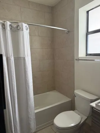 a white toilet and tub sitting next to a window