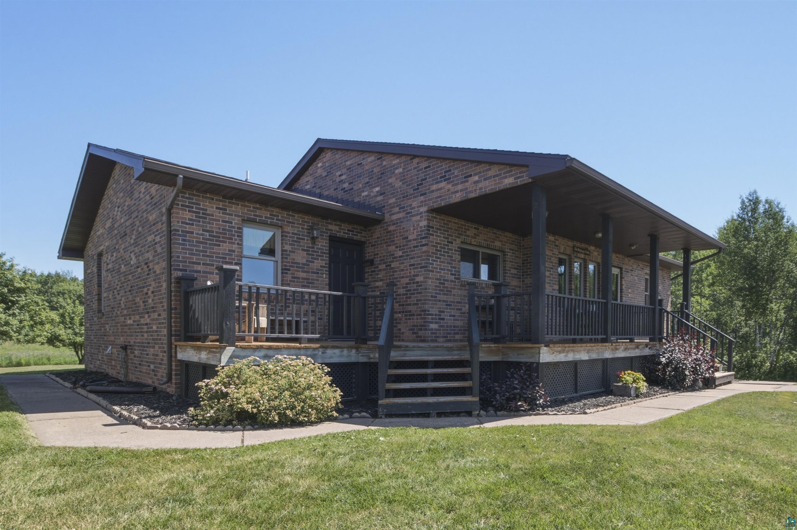 64260 Jolma Road Ashland, WI 54806 - Photo 3 of 35 Brick exterior with a covered porch featuring dark wood railings and supporting columns