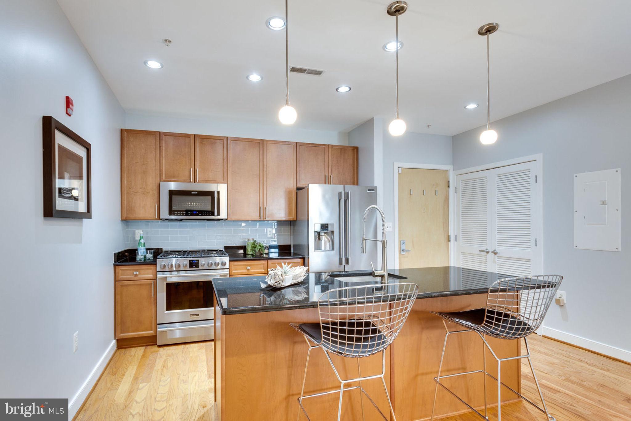 181 East Reed Avenue, Unit 109 Alexandria, VA 22305 - Photo 6 of 30 a kitchen with stainless steel appliances a stove a refrigerator a oven a sink with white cabinets and wooden floor
